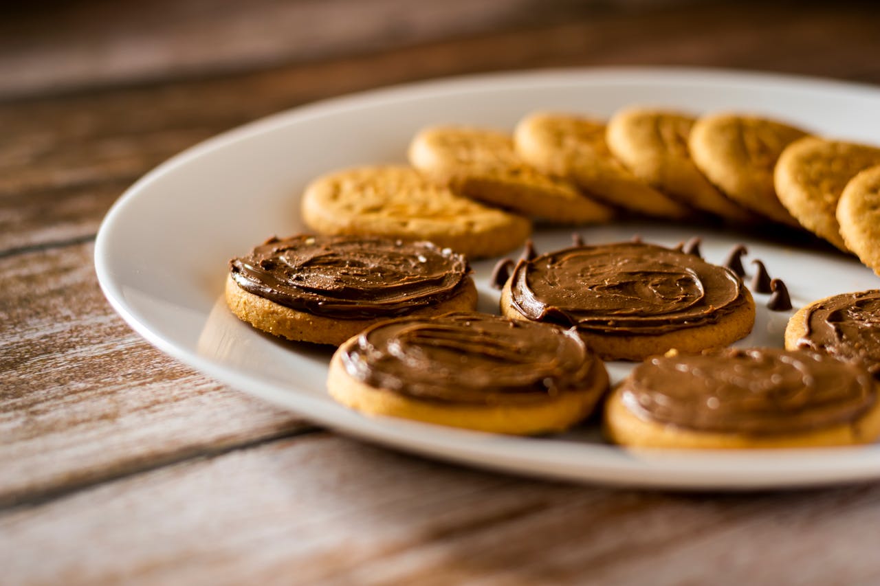 Delicious biscuits topped with rich chocolate spread on a rustic wooden surface.
